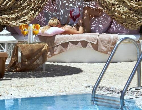 a woman laying on a couch next to a swimming pool at Apsenti couples only in Agios Ioannis Mykonos