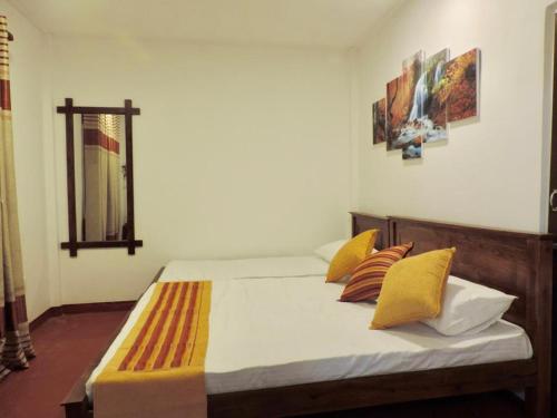 a bedroom with a bed with yellow pillows at Athens Nuwara Eliya Villa in Nuwara Eliya