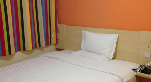a white bed in a room with a colorful wall at 7 Days Inn Hohhot Hailiang Xinhua Square Metro Station in Hohhot