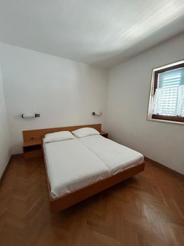 a white room with a bed and a window at Apartments BEVANDA in Šimuni