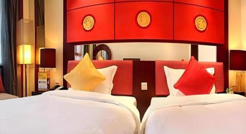 a bedroom with two beds with red and yellow pillows at Dunhuang Grand Soluxe Hotel in Dunhuang