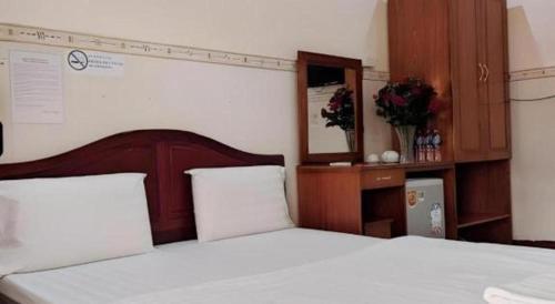 a bedroom with a white bed with a wooden headboard at Quang Sang Hotel Can Tho in Can Tho