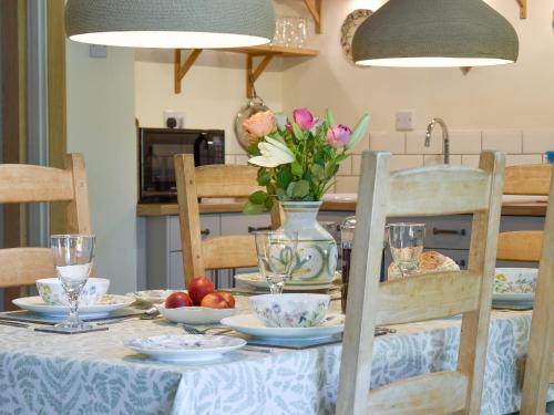 a dining room table with a vase of flowers on it at Beech Tree Cottage At Blackaton Manor Farm in Widecombe in the Moor