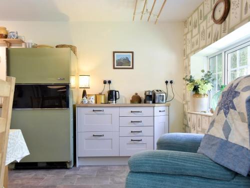 a kitchen with white cabinets and a refrigerator at Beech Tree Cottage At Blackaton Manor Farm in Widecombe in the Moor