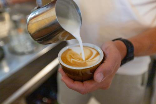 a person pouring milk into a cup of coffee at Penzion UNA in Liptovský Ján