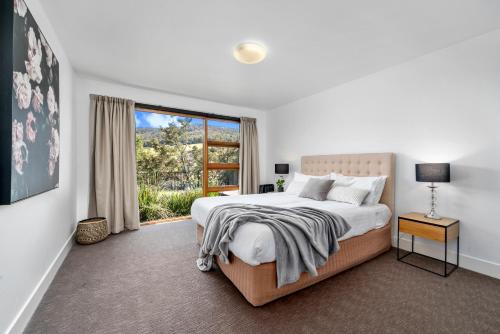 a bedroom with a bed and a large window at Huon Valley House in Ranelagh
