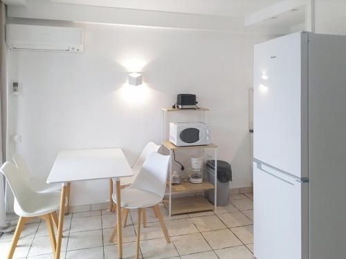 La cuisine est équipée d'une table et de chaises blanches ainsi que d'un réfrigérateur blanc. dans l'établissement Résidence Graziella Studio 502, à Juan-les-Pins