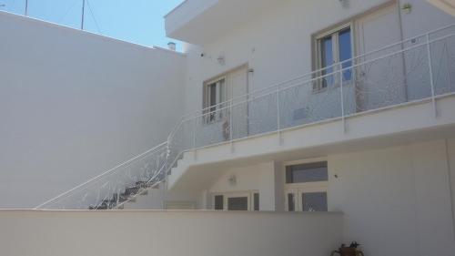 um edifício branco com uma varanda com escadas em Corallo Home em Carovigno