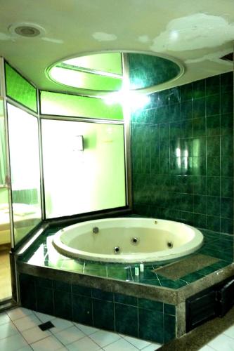 a bathroom with a tub with a green tiled wall at Lips Motel (Adult Only) in Rio de Janeiro