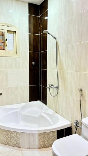 a bathroom with a bath tub and a toilet at شاليهات ووحدات فندقية وشقق مفروشة بالباحة - العقيق in Al ‘Aqīq