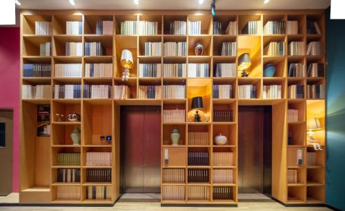a library with wooden shelves with books at Happy Inn-Xinzheng International Airport Branch喜鹊愉家连锁酒店-机场店 in Zhangzhuangjie