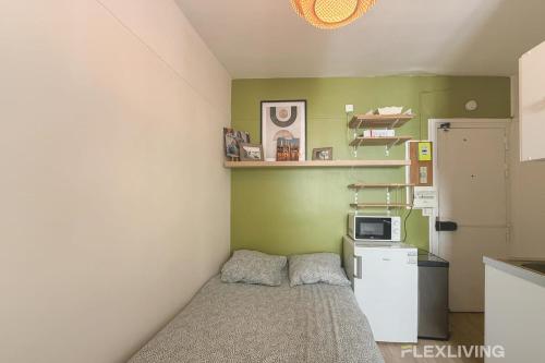 Cette petite chambre comprend un lit et un petit réfrigérateur. dans l'établissement Flexliving - Studio - Hopital, à Paris
