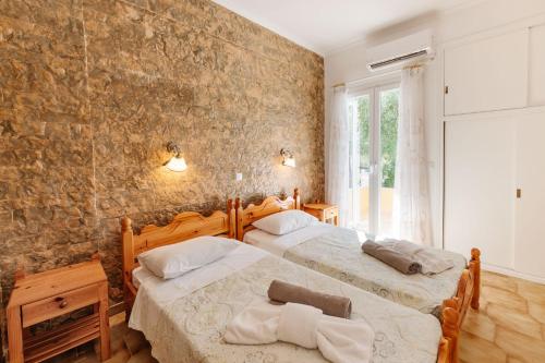 two beds in a bedroom with a stone wall at Villa-Toula in Roda