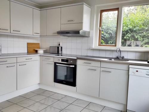 a kitchen with white cabinets and a sink and a window at Waterfront house with big garden in Arnemuiden