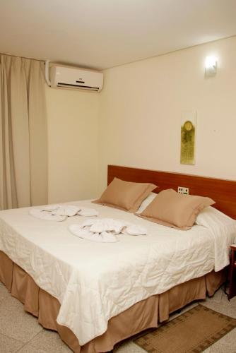 a bedroom with a large white bed with flowers on it at Royal Inn Hotel in Cornélio Procópio