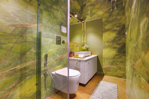 a bathroom with a toilet and a glass shower at SaffronStays Miorah in Bhowāli