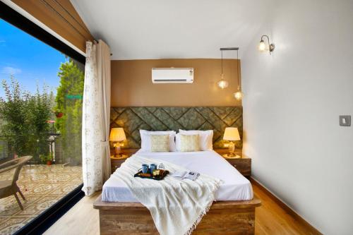 a bedroom with a bed and a large window at SaffronStays Miorah in Bhowāli