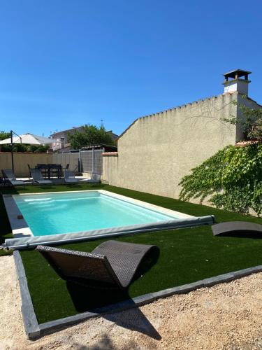 - une piscine avec une chaise à côté d'un mur dans l'établissement Maison avec piscine et jardin, à Salses-le-Chateau