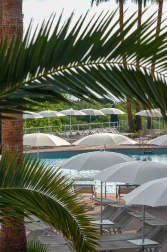 a pool with white umbrellas and chairs and tables at Thalazur Antibes - Hôtel & Spa in Antibes