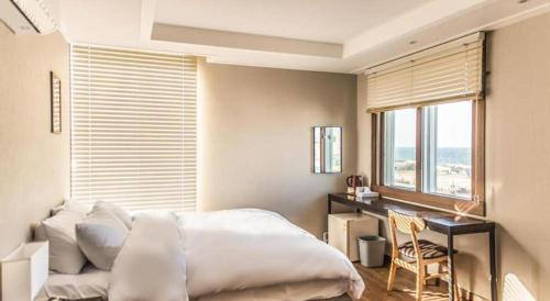 a bedroom with a bed and a desk and a window at Check Inn Hotel in Jeju