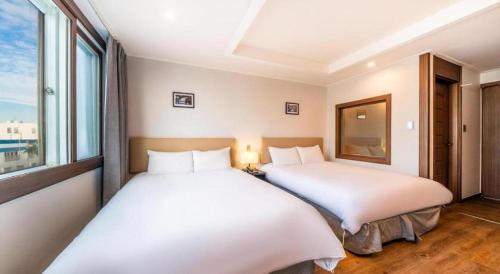 two beds in a room with two windows at Check Inn Hotel in Jeju