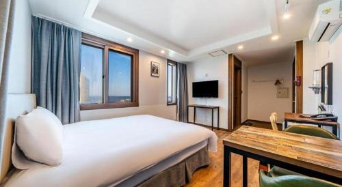 a hotel room with a large bed and a desk at Check Inn Hotel in Jeju