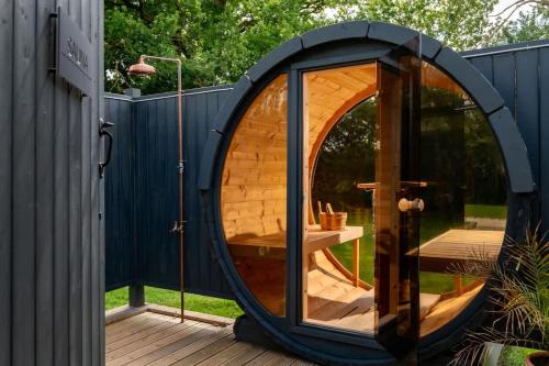 an igloo house with a glass door on a deck at Rabbits Warren - Cotswolds Stay with Sauna and Hot Tub in Hankerton