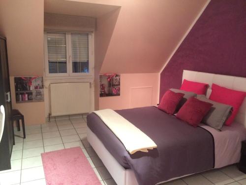 a bedroom with a bed with purple walls and red pillows at L'Eden Orly Aéroport in Thiais