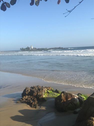 a beach with rocks in the sand and the ocean at Namastay Homes in Kovalam