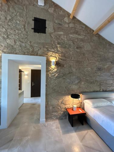 a bedroom with a bed and a stone wall at Arume Rural House in Catasueiro
