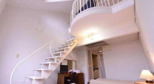 a white spiral staircase in a living room at Petit Hotel Key West Club in Naha