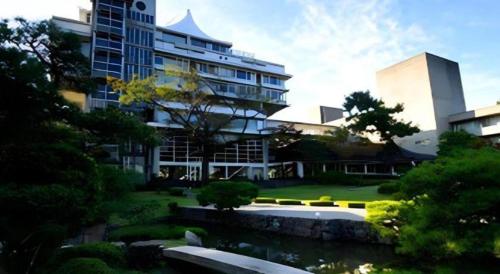 a large building with a pond in front of it at Hotel Tokoen in Yonago