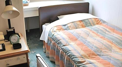 a bedroom with a bed and a table with a clock at Hotel Abest Aomori in Aomori