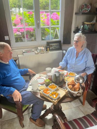 an older man and woman sitting at a table with food at Manoir La Tasserie in Saint-Philbert-des-Champs