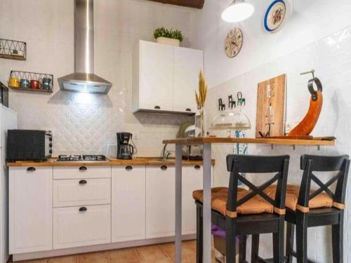 a kitchen with white cabinets and black chairs at Casa Crisantemo with sea view and pool in Adra in Las Hoyas del Barranco