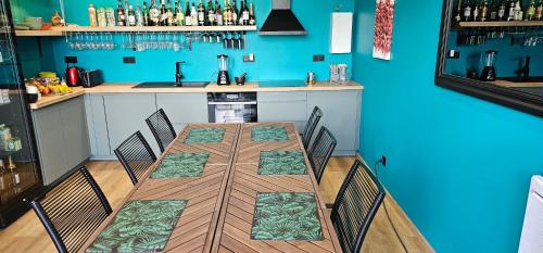 een kamer met een tafel met stoelen en een blauwe muur bij Abaca Colors in Saint-Martin-de-Seignanx