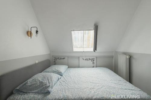 un lit dans une chambre blanche avec une fenêtre dans l'établissement Flexliving - Studio - Tour Maubourg, à Paris