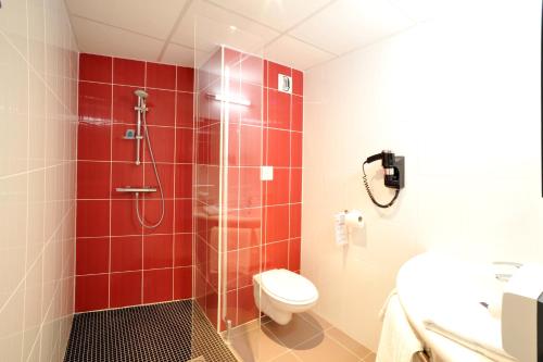 a bathroom with a toilet and a shower with red tiles at The Originals City, Hotel Novella Premium, Nantes Est in Carquefou