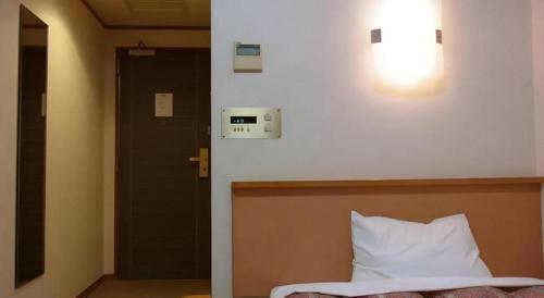 a bedroom with a bed and a light on the wall at Chino Station Hotel in Chino