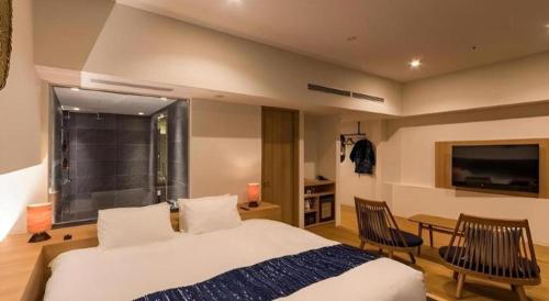 a bedroom with a bed and two chairs and a television at HOTEL CLAD in Fuji