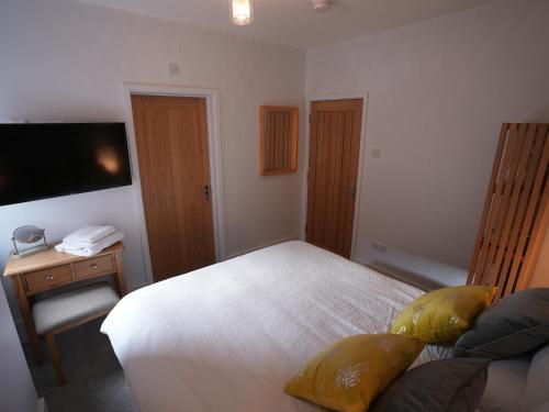 a bedroom with a white bed and a television at Romsey Brewery House - circa 1893 in Romsey