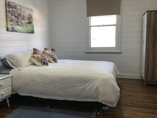 a bedroom with a bed with white sheets and a window at Yallamatta Bed and Breakfast in Apsley