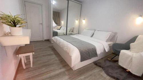 a bedroom with a large white bed and a chair at DreamApartment in Deva