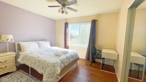 Un dormitorio con una cama con ventilador de techo y una ventana. en New - Spacious, Comfortable 5 Beds 3 Baths House, en Elk Grove