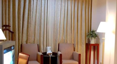 a room with two chairs and a tv and curtains at Quanzhou Overseas Chinese Hotel in Quanzhou