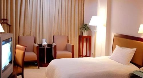 a hotel room with a bed and two chairs and a television at Quanzhou Overseas Chinese Hotel in Quanzhou
