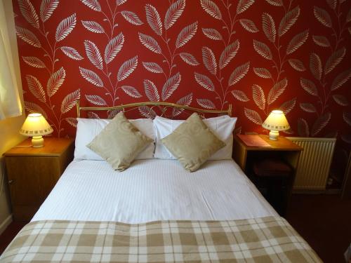 a bedroom with a white bed with a red wall at The Belvedere in Blackpool