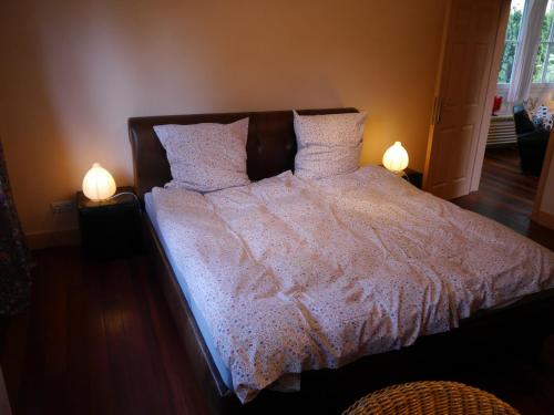 a bed with a white comforter and two lamps at Haus Honigstal Landhaus Café in Wuppertal