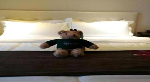 a stuffed teddy bear sitting on a bed at James Joyce Coffetel·Shijiazhuang Economic and Technological Development Zone Chuangye Road in Shijiazhuang