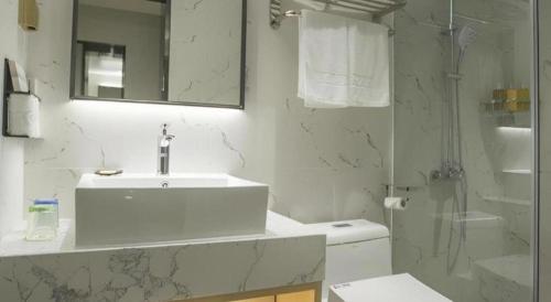 a white bathroom with a sink and a shower at Borrman Hotel Zhuhai Gongbei Port Fuhuali Light Rail in Zhuhai